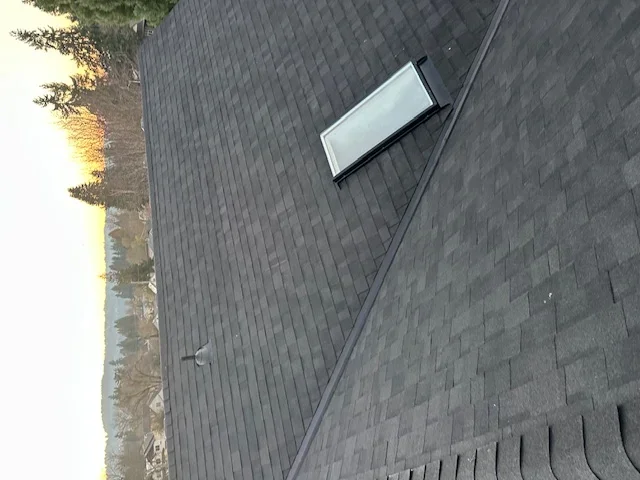 Dark gray asphalt shingle roof with white roof vent installed on residential home