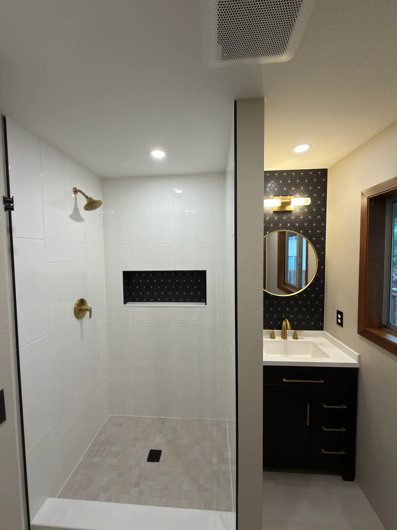 Modern bathroom with white tile shower, black vanity, and geometric accent wall