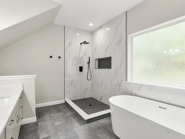Master bathroom renovation by Kenai Construction featuring marble tile shower and freestanding tub