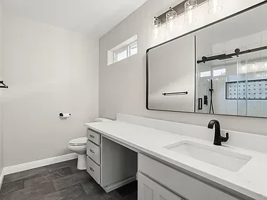 Modern bathroom with white vanity, quartz countertop, dual mirrors, and dark tile flooring