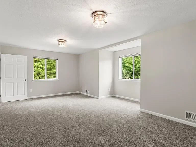Freshly painted interior room with gray carpet, white trim, and ceiling fixtures