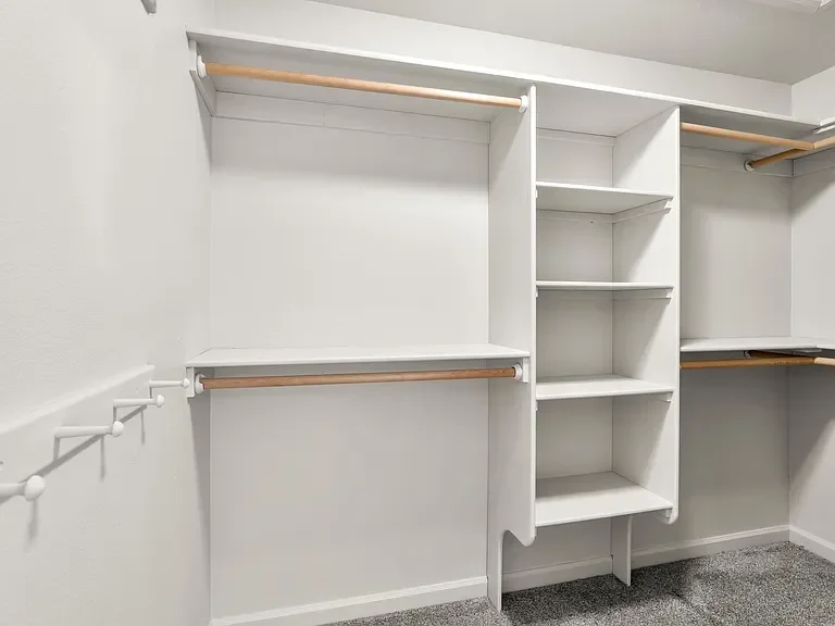 White custom closet with dual hanging rods, open shelving, and organized storage compartments