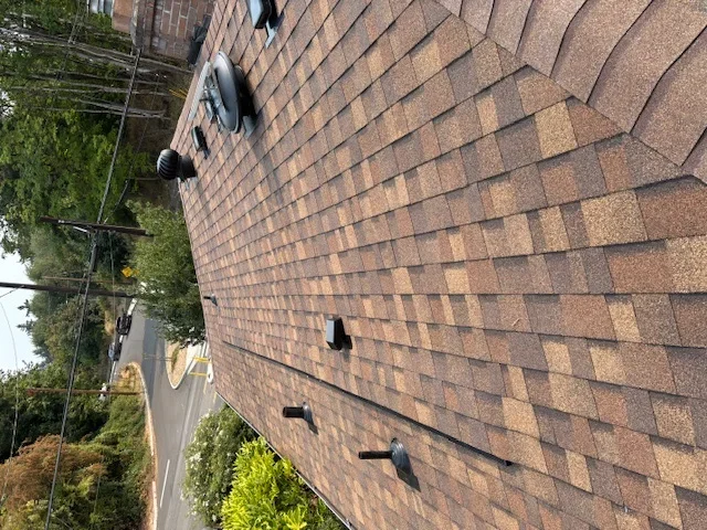 Newly installed brown architectural shingles on residential roof with proper flashing details