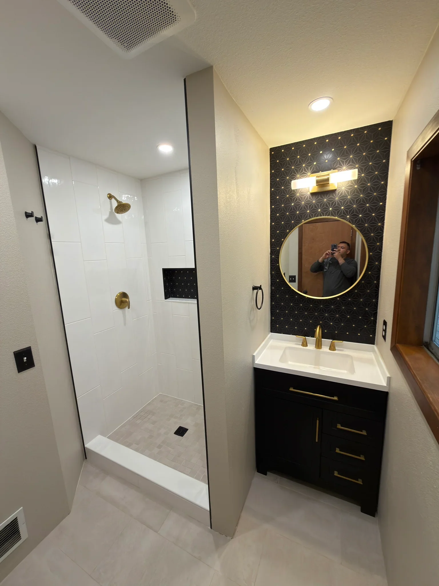Modern bathroom remodel with walk-in shower and black accent wall by Kenai Construction
