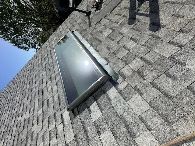 Installed skylight with aluminum frame on pitched asphalt shingle roof