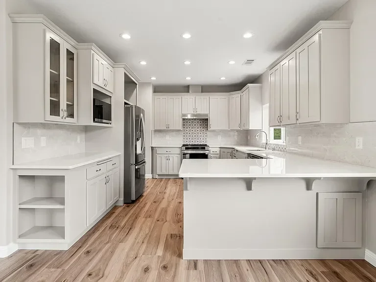 Bright modern kitchen with white cabinets, quartz counters, and wood flooring