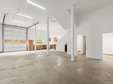 Bright, renovated garage interior with white walls, concrete floor, and wooden storage shelves