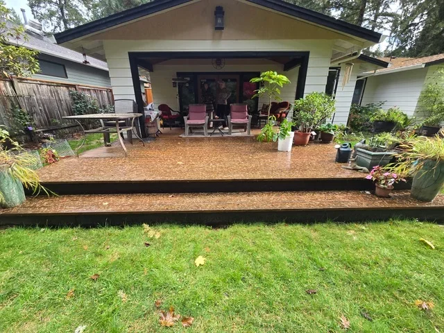 Completed backyard patio with bark mulch surface and steel edging, adjacent to white home with covered porch